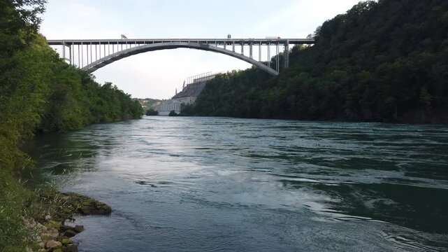 The Niagara River and the Queenston&ndash;Lewiston Bridge, a border crossing between the United States and Canada, as seen from the Niagara Gorge. Tilting up. Ontario Power Generation center seen in the bac