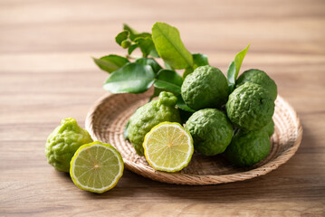 Kaffir lime fruit with leaf in basket on wooden background, Thai food ingredient