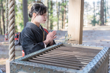 神社でお参りする着物姿の女性
