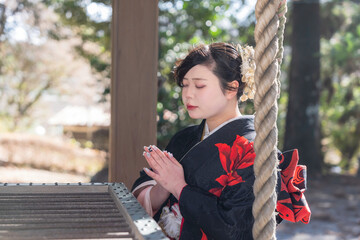 神社でお参りする着物姿の女性