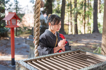 神社でお参りする着物姿の女性