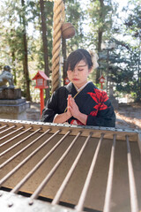 神社でお参りする着物姿の女性
