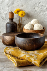 Rustic wooden bowls and yellow flowers on a textured surface