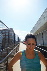Fototapeta premium Fitness, woman and walking outdoor on bridge with running break, workout pause and breathe for recovery. Space, female person and runner in city with cardio exercise rest, contemplation and wellness.