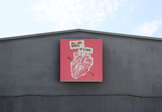 A blank square billboard mockup is displayed on a gray building against a clear sky. PSD template mockup.