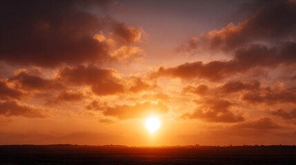A vibrant fiery sunset glows dramatically through textured clouds over a serene dark landscape