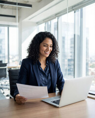 Focused latin business woman accountant working on laptop computer reading financial contract document in office workplace. Mature manager businesswoman specialist doing paperwork using pc. Copy space