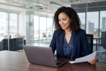 Focused latin business woman accountant working on laptop computer reading financial contract document in office workplace. Mature manager businesswoman specialist doing paperwork using pc. Copy space