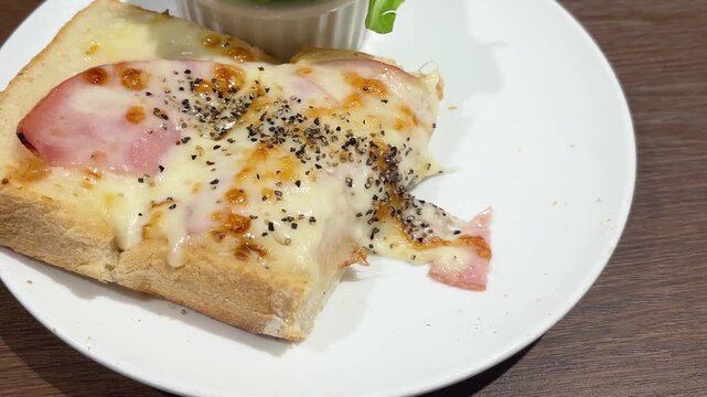 朝食のクロックムッシュ。ハムとチーズをトッピングしたトーストをちぎって食べる動画のクローズアップ。