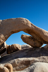Natural granite arch formation under clear desert sky