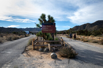 Hikers walking past Black Rock Canyon Campground sign in desert