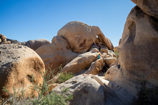 Tourists explore giant desert boulders and natural rock arch
