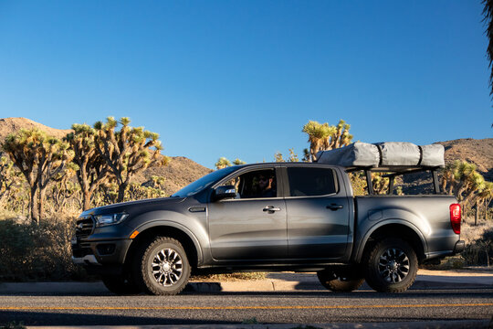 Overland pickup truck parked on desert road under clear blue sky