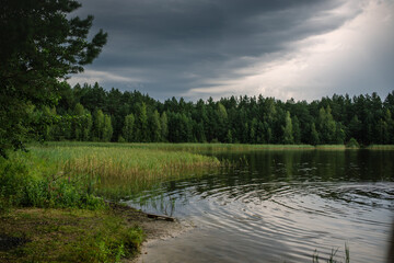 Calm lake before a thunderstorm in a northern forest