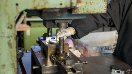 Industrial worker positioning metal part on press mold during manufacturing process