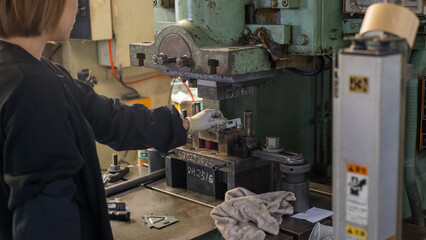 Industrial worker operating press machine with metal mold in small factory