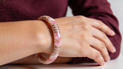 Woman wearing a pink patterned bangle bracelet on her wrist  