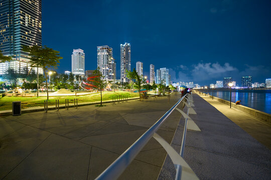 Waterfront promenade at night with urban skyline lights