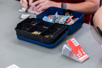 Cash box with raffle ticket book on table and person selling raffle tickets