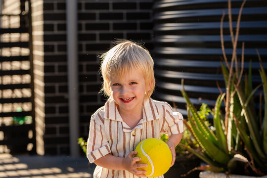 Boy playing in suburban backyard with yellow ball