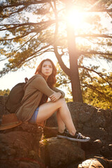Think, hiking and woman in nature on break for travel, holiday and eco tourism with flare in forest. Rest, person and backpacker in woods for reflection, vision and relax outdoor on adventure