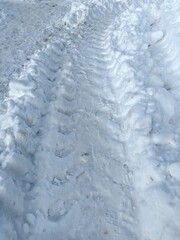 Obraz premium Traces of car or tractor wheels in the snow on a winter day, tread marks.
