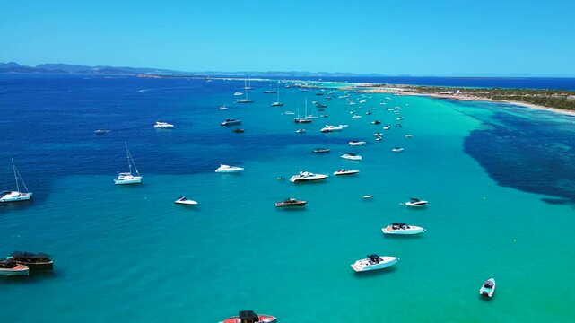 many pleasure boats anchored in the clear turquoise waters of Formentera high society Balearic island. Magic aerial view panorama overview static tripod hovering drone