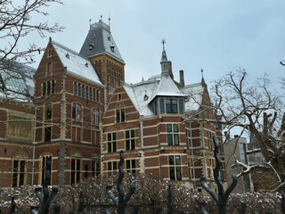 Iconic Rijksmuseum building in Amsterdam covered in snow. Historic Dutch red brick Neo-Gothic architecture in a tranquil winter cityscape