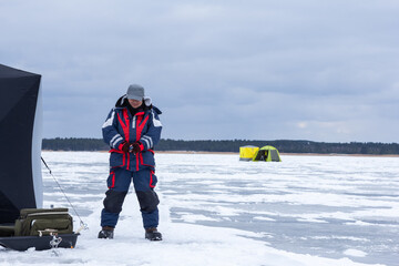 Ice fishing. Ice fisherman catching fish in a hole. Ice fishing for smelts in the Curonian Lagoon, Lithuania