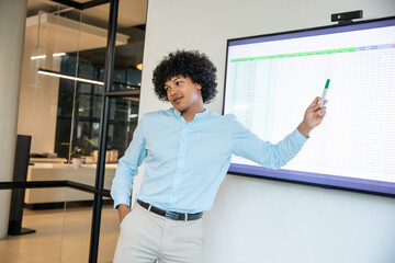 African american man presenting spreadsheet on screen in office holding marker leaning near wall