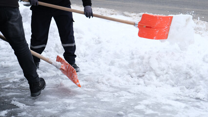 Municipal workers are cleaning the sidewalks blocked by snow. snow removal workers with snow shovels © MahmutSonmez