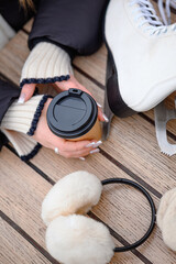 woman holding a hot drink in her hand on the ice rink. red glass