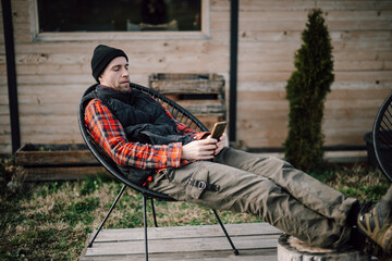 Man sitting outside on a chair and using a smartphone