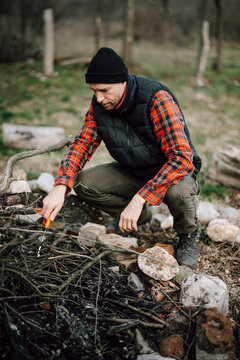 Man gathers sticks and prepares campfire in forest