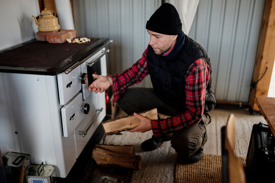Man places wood in stove while preparing for cooking