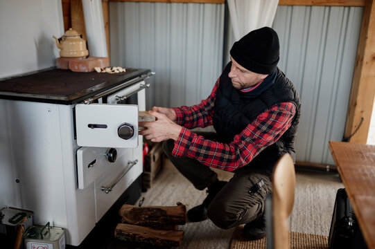 Man prepares food using a vintage stove in a cozy kitchen