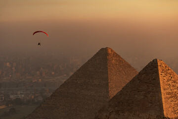 Aerial view of the ancient pyramids standing tall against the horizon, with a paraglider floating, Cairo, Egypt.