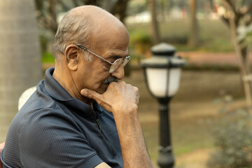 Portrait of a Indian sad, depression, thinking, Upset lonely homeless senior man in garden sitting...