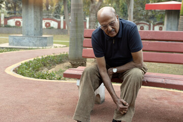 Obraz premium Portrait of a Indian senior man suffering from knee pain at park