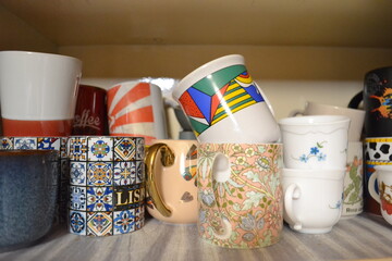 Assorted Patterned Coffee Mugs and Cups Stored on a Kitchen Shelf