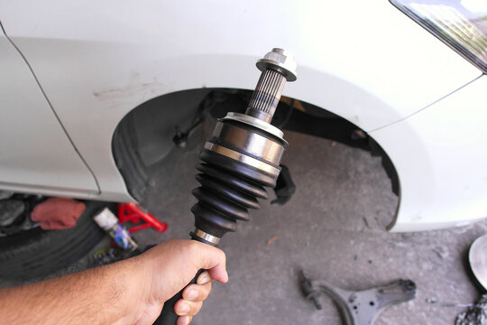 New CV Joint Installation, A mechanic holds a new CV axle joint with a protective rubber boot, ready for installation to fix car vibration and drive issues.