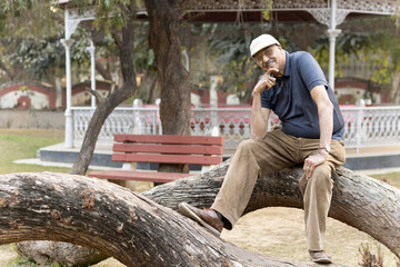 Fototapeta premium Indian happy senior man feels freedom, fun and spending leisure time at the park after retirement