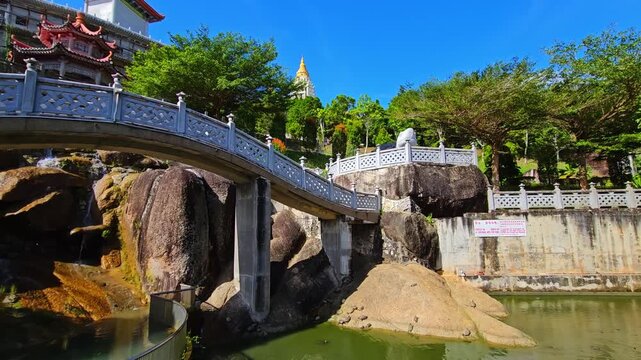 Kek Lok Si Buddhist temple complex on hillside in Penang, Malaysia. Colorful pagodas, shrines and white tower with golden spire surrounded by lush green trees. Traditional Asian architecture under