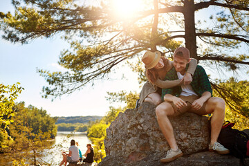 Happy, couple and hiking with hug outdoor for travel, trekking adventure and partner affection. Smile, people and embrace with support, backpacking date and bonding together on vacation trip in woods