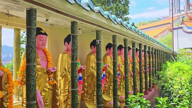 Kek Lok Si Buddhist temple complex on hillside in Penang, Malaysia. Golden Buddha statues in a Buddhist temple with sacred symbols and floral garlands, symbolizing spirituality, meditation, and