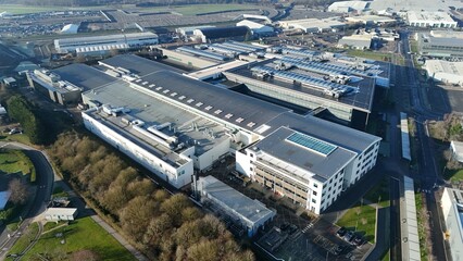 Aerial view of modern industrial architecture, with sprawling buildings and verdant surroundings, bathed in the soft glow of daylight, Warwick, England, United Kingdom.