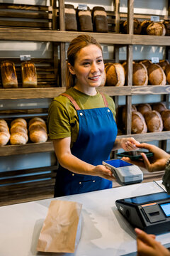 Bakery worker accepting mobile payment from customer at counter