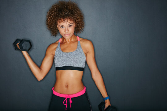 Exercise, weights and portrait of woman in studio for fitness, strength training and bodybuilding. Mockup space, workout and person with dumbbells for muscle, strong arms or health on gray background