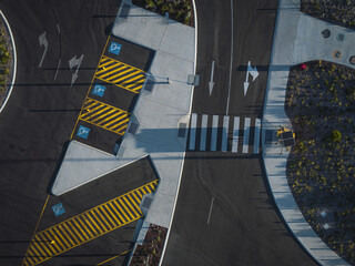 Aerial view of crisp white pedestrian lines cutting through the dark asphalt, contrasting with the yellow striped parking zones and blue disability symbols, Ocean Reef, Western Australia, Australia.