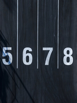 Aerial view of numbers 5, 6, 7, and 8 aligned vertically with stark white against a dark background, Ocean Reef, Western Australia, Australia.